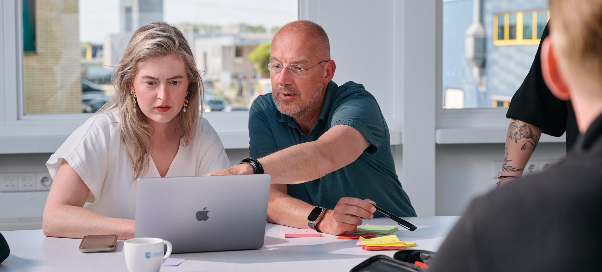 Man helpt vrouw achter laptop