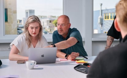 Man helpt vrouw achter laptop